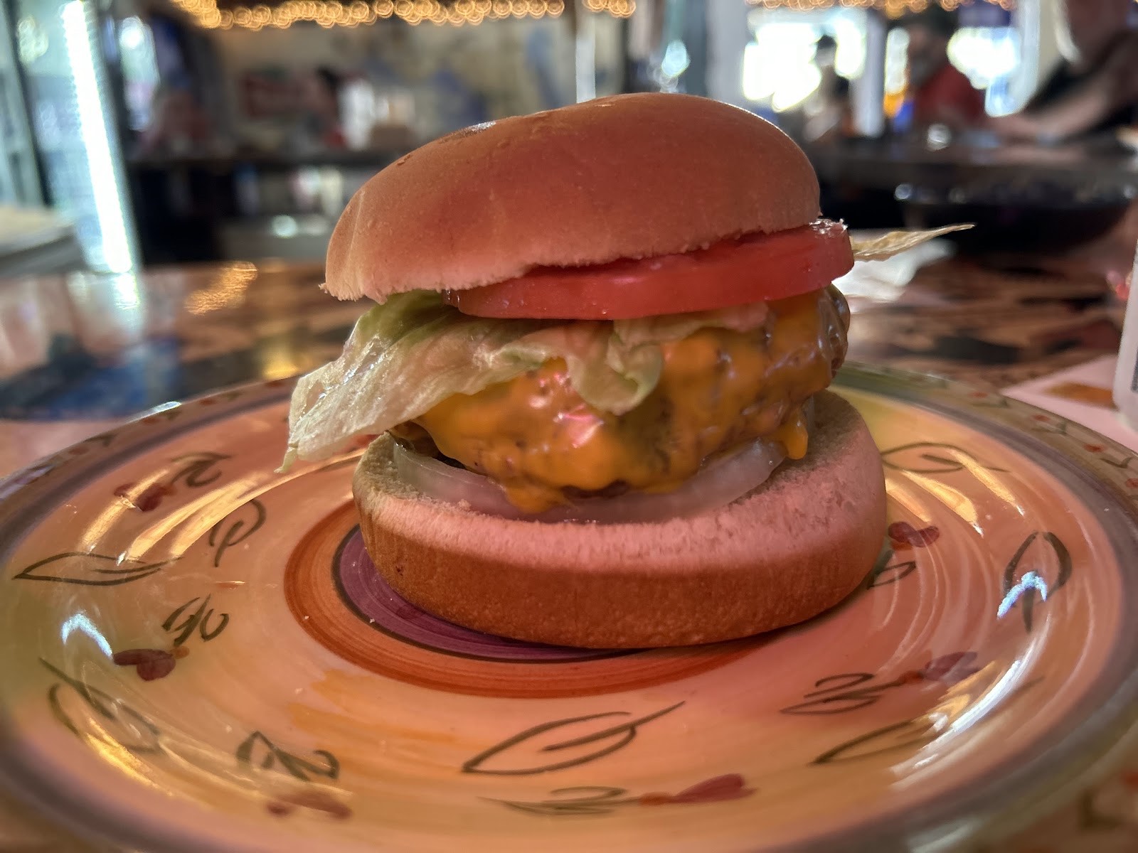 A classic Hi Way Bar cheeseburger with lettuce and tomato served on a hand-painted plate